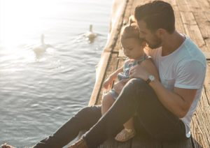 dad cuddling daughter on a dock